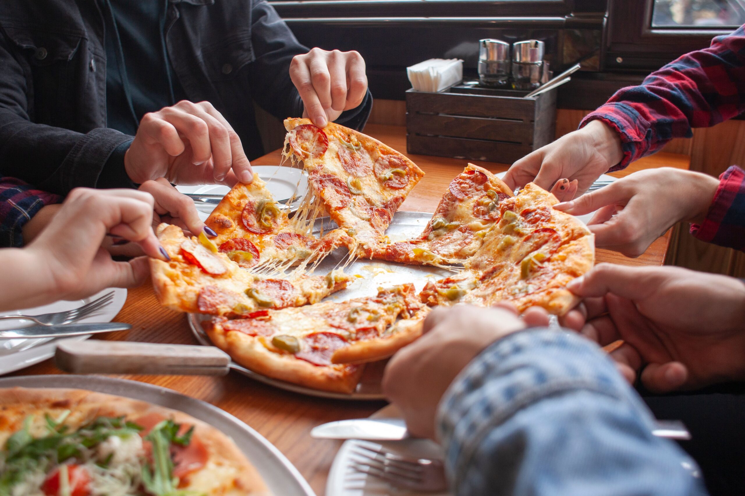 friends sharing pepperoni pizza slices scaled