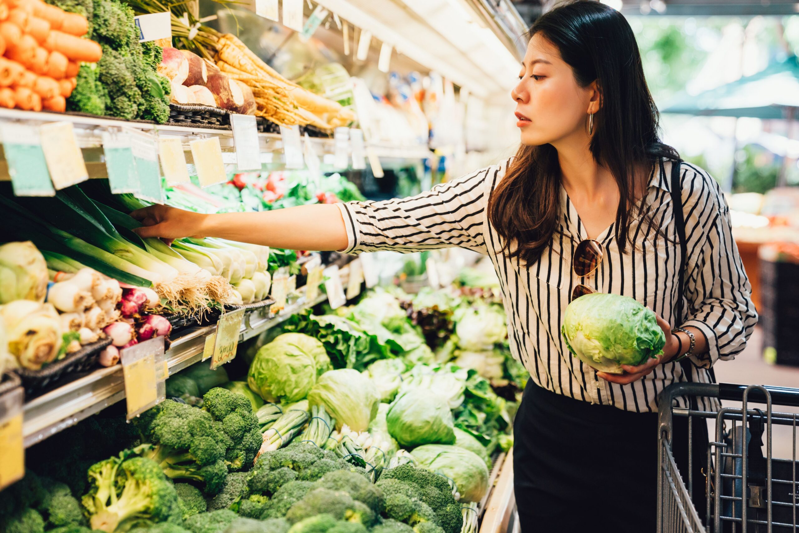 woman choosing vegetables grocery store scaled